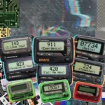A retro glitch art collage of various 1990s pagers and beepers displaying numeric codes like 143 and 911 against a grainy, neon-distorted background.